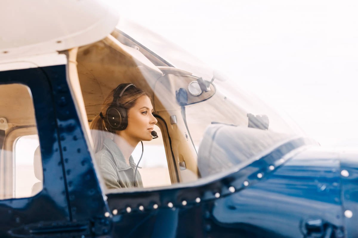 Woman,Pilot,In,Airplane,Cockpit,,Wearing,Headset,With,Microphone.